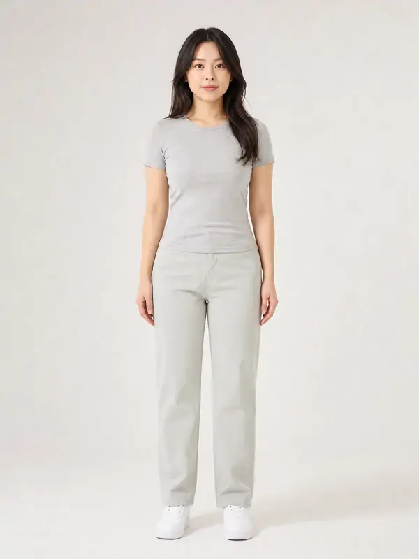 グレーの半袖Tシャツとパンツで正面を向いて立つ女性の全身写真の例。AIで作成した架空の人物です。